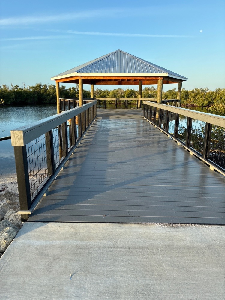 Boardwalk with railings leading to a covered observation deck over the water at Tropicana Park, with mangroves along the shoreline.